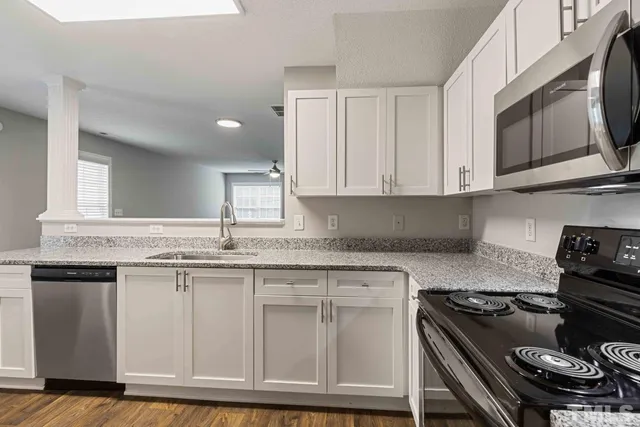 a kitchen with granite countertop a stove sink and cabinets