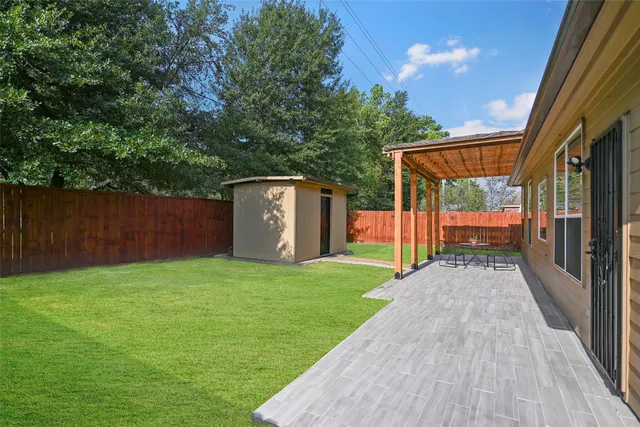 a view of a backyard with large trees and wooden fence