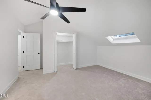 an empty room with closet area and a chandelier fan