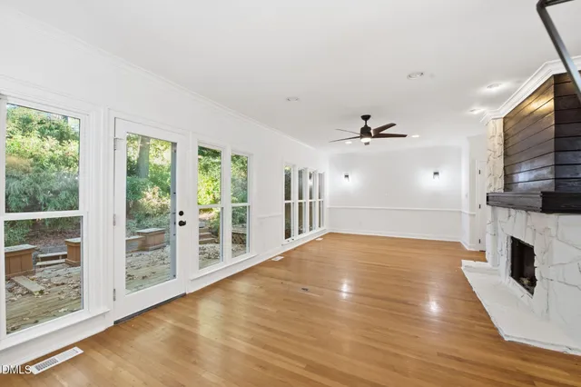 a view of an empty room with wooden floor and a window