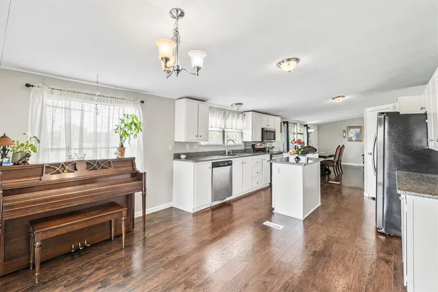 a kitchen with kitchen island a refrigerator cabinets and wooden floor