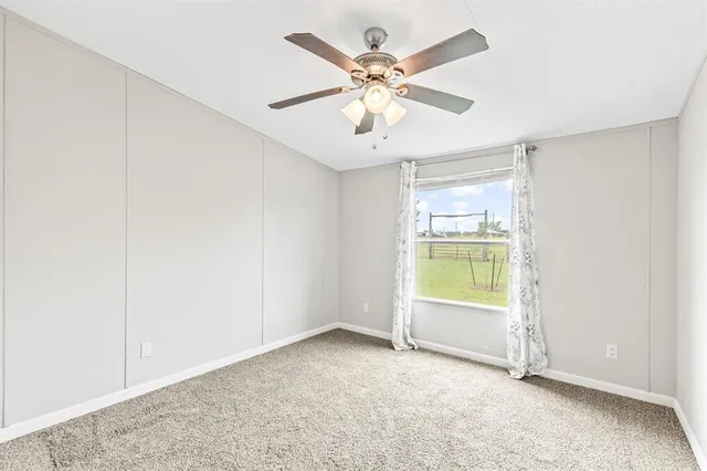 an empty room with a chandelier fan and windows