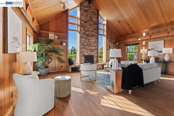 a living room with furniture a large window and wooden floor