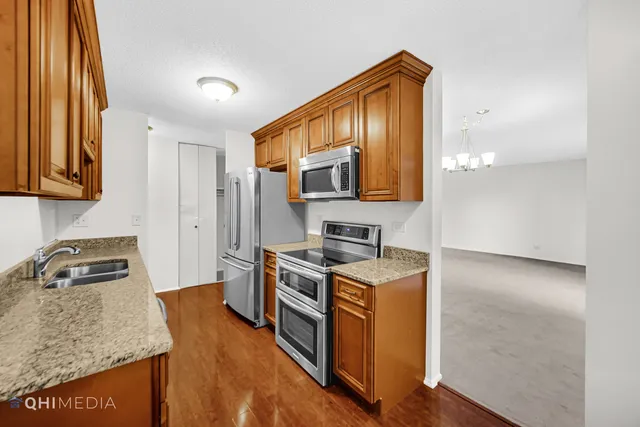 a kitchen that has a sink wooden cabinets and stainless steel appliances