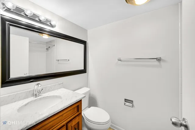 a bathroom with a granite countertop sink mirror vanity and toilet