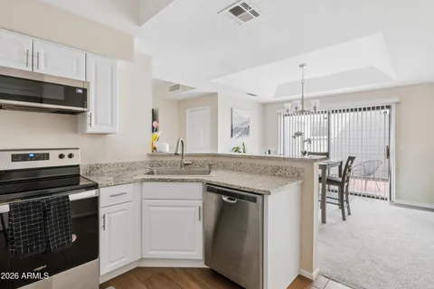 a kitchen with kitchen island granite countertop a stove top oven a sink dishwasher a dining table and chairs with wooden floor