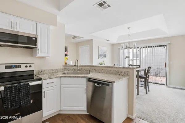 a kitchen with kitchen island granite countertop a stove top oven a sink dishwasher a dining table and chairs with wooden floor