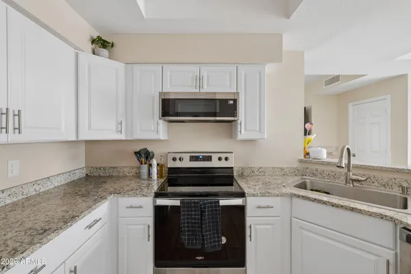 a kitchen with granite countertop a stove a microwave a sink and cabinets