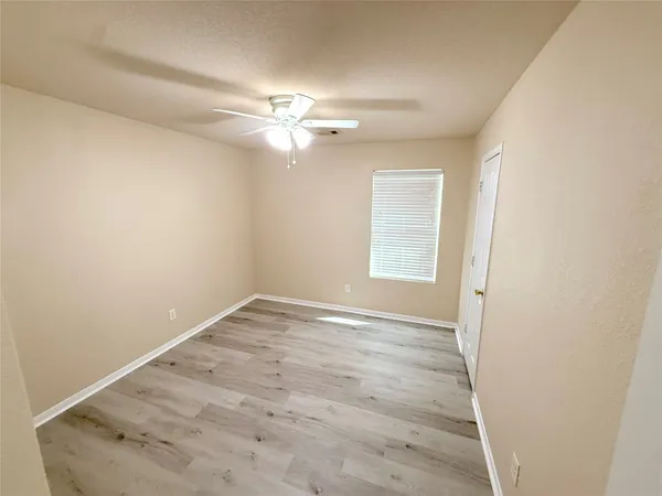 an empty room with windows and fan