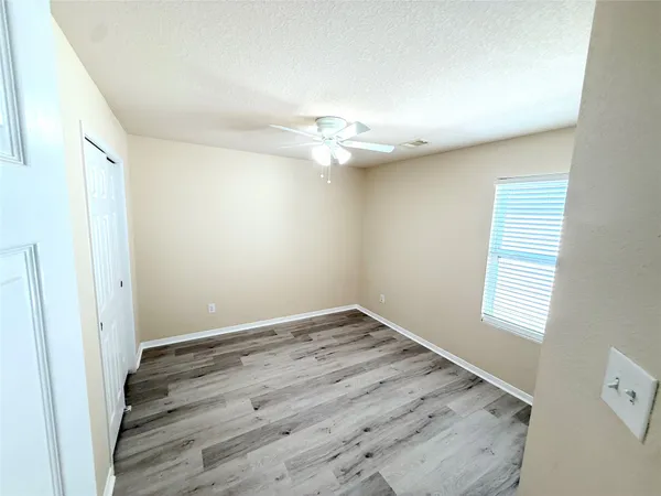 an empty room with a window and a ceiling fan