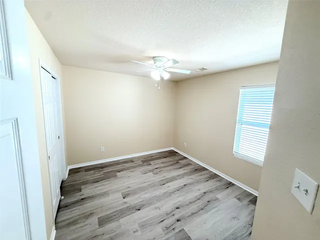 an empty room with a window and a ceiling fan
