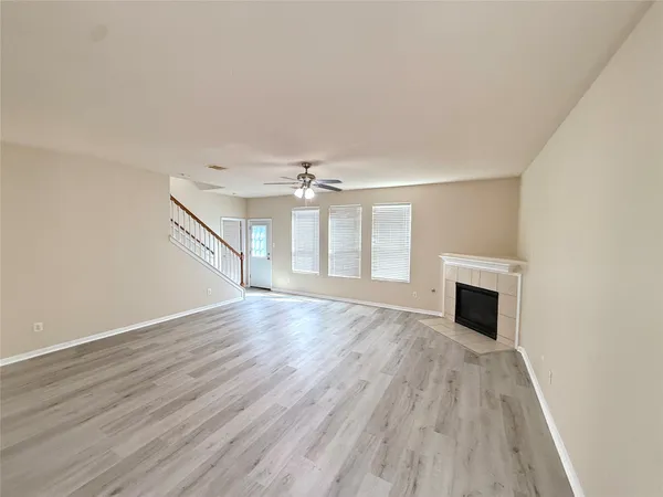 an empty room with wooden floor fireplace and windows