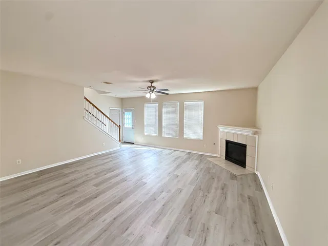 an empty room with wooden floor fireplace and windows