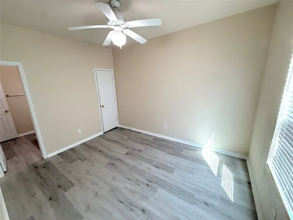 an empty room with wooden floor fan and windows