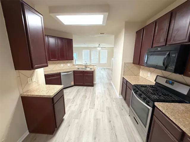 a kitchen with kitchen island granite countertop wooden cabinets a stove top oven a sink and dishwasher