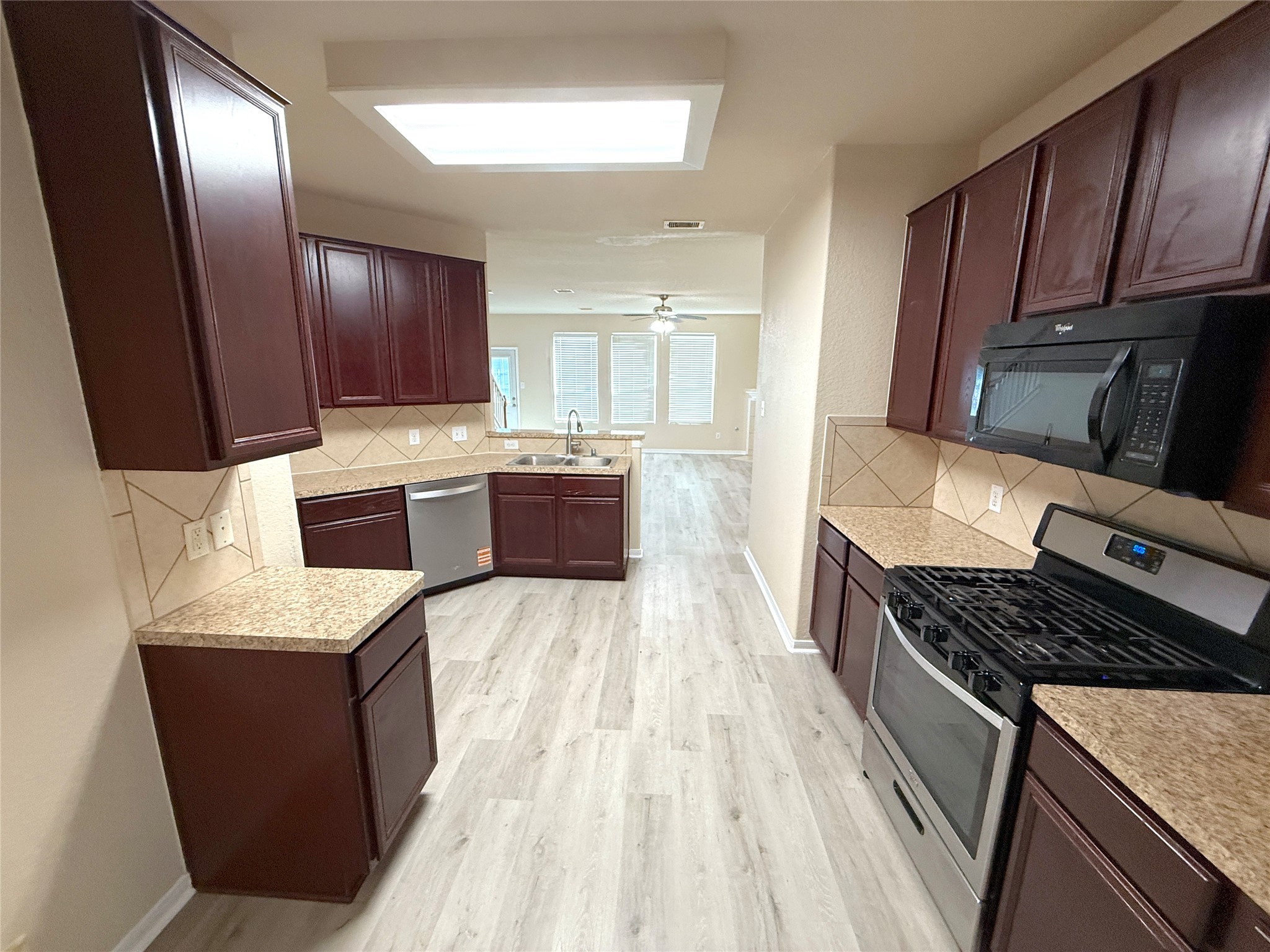 19535 Hardwood Ridge Trail Cypress, TX 77429 - Photo 7 of 15 a kitchen with kitchen island granite countertop wooden cabinets a stove top oven a sink and dishwasher