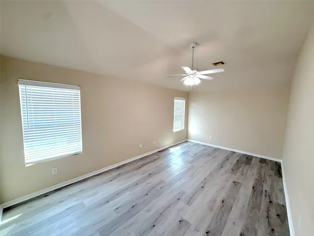 an empty room with wooden floor and windows