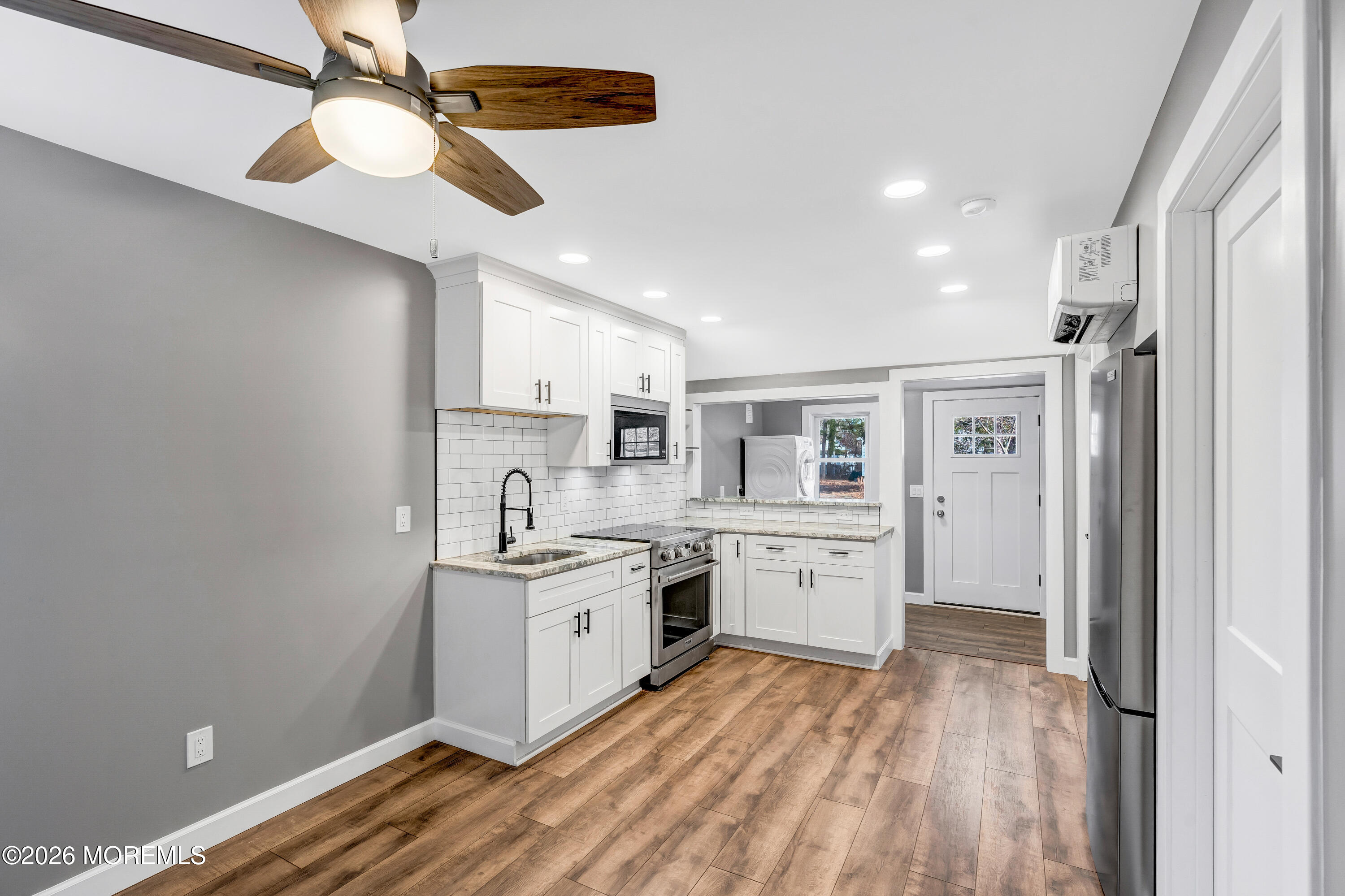 32 Chestnut Street Waretown, NJ 08758 - Photo 10 of 35 a kitchen with a sink dishwasher a stove and white cabinets with wooden floor