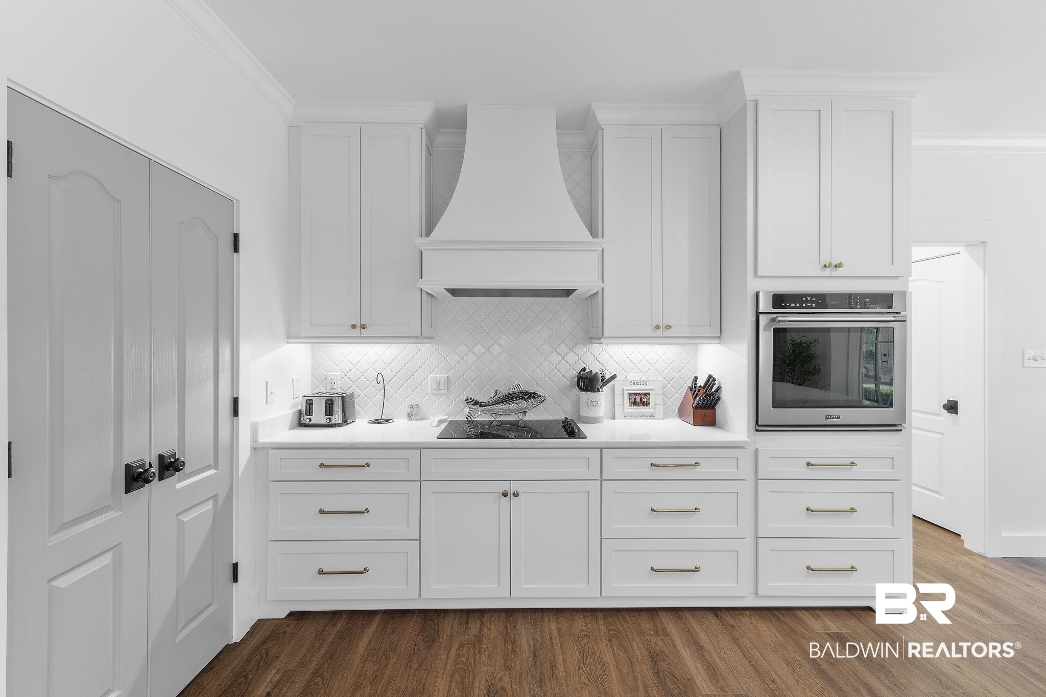 4451 Millhouse Road Gulf Shores, AL 36542 - Photo 19 of 50 Kitchen with oven, custom exhaust hood, wood-type flooring, and white cabinets