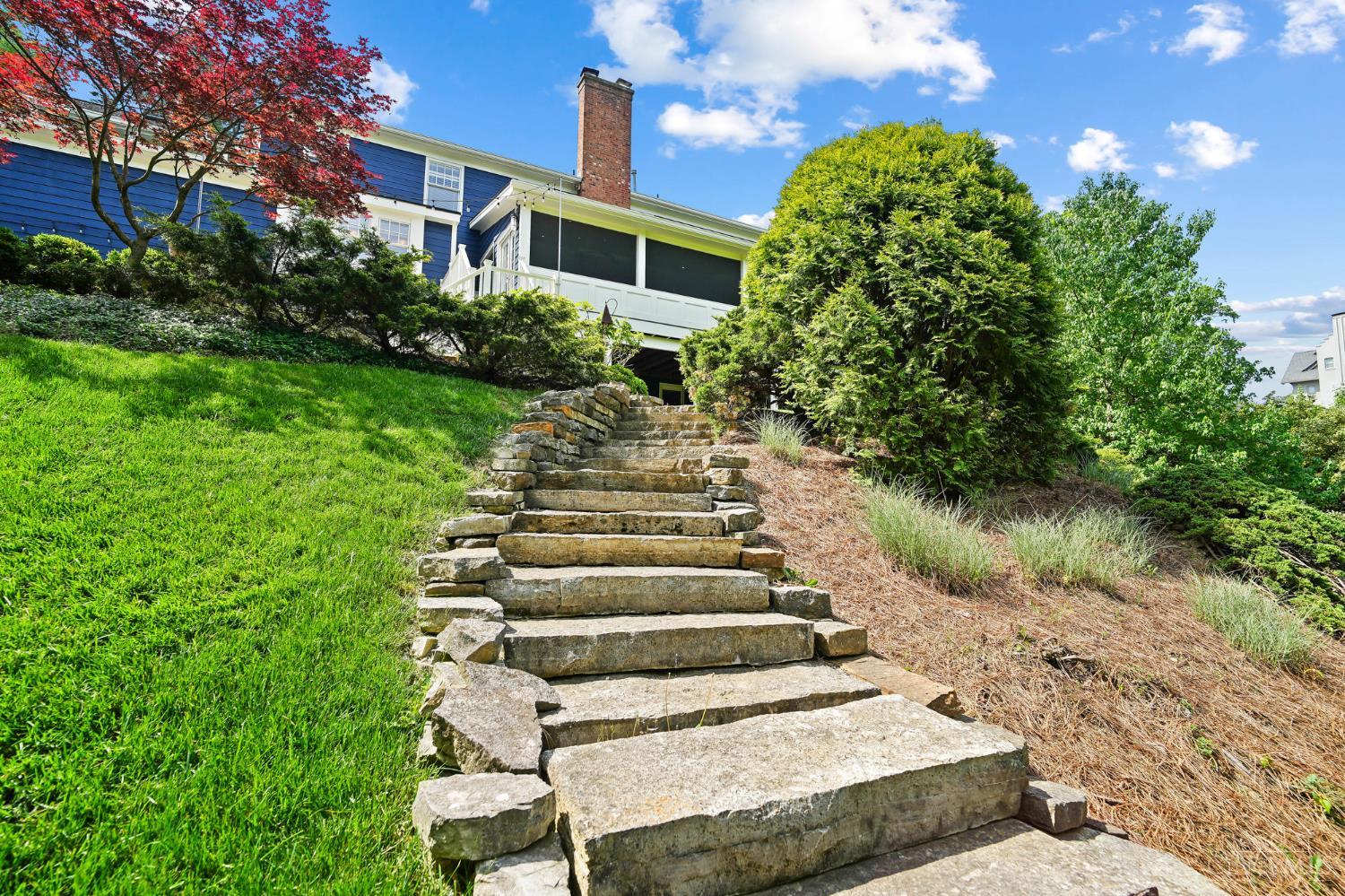 2780 Walsh Road Cincinnati, OH 45208 - Photo 55 of 68 The rear yard offers a beautiful blend of structure and natural serenity, with thoughtfully placed stepping stones and a stone stairway that gently guide you to a lush, expansive lawn. Set on a private 1.5-acre lot, the property is surrounded by mature trees, creating a peaceful, park-like setting with both open green space and wooded privacy—ideal for outdoor enjoyment, play or quiet retreat.