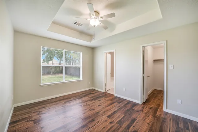 a view of an empty room with a window and wooden floor