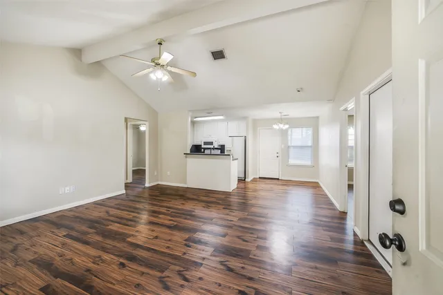 a view of an empty room with wooden floor and a ceiling fan