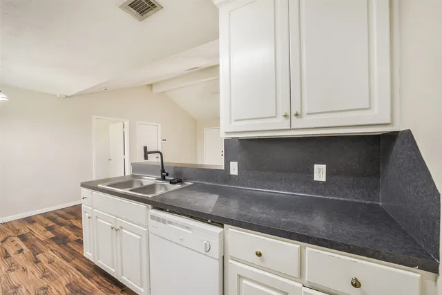 a kitchen with granite countertop white cabinets and a sink