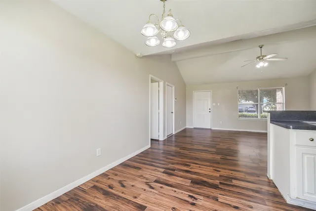 a view of a livingroom with a chandelier fan and wooden floor