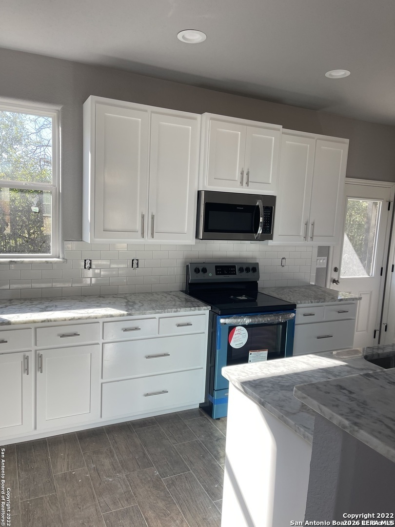 107 Sutton Place Uvalde, TX 78801 - Photo 5 of 11 a kitchen with granite countertop a sink a stove top oven a counter space and cabinets