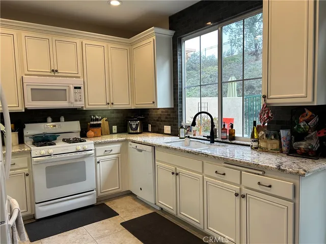 a kitchen with granite countertop white cabinets and white appliances