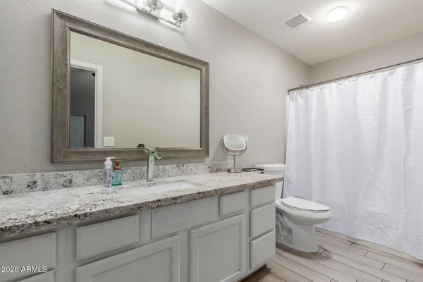 a bathroom with a granite countertop sink toilet and mirror