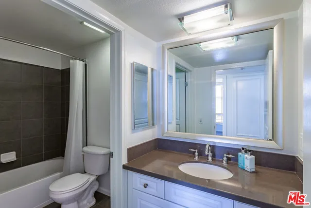 a bathroom with a granite countertop sink toilet a mirror a vanity and shower