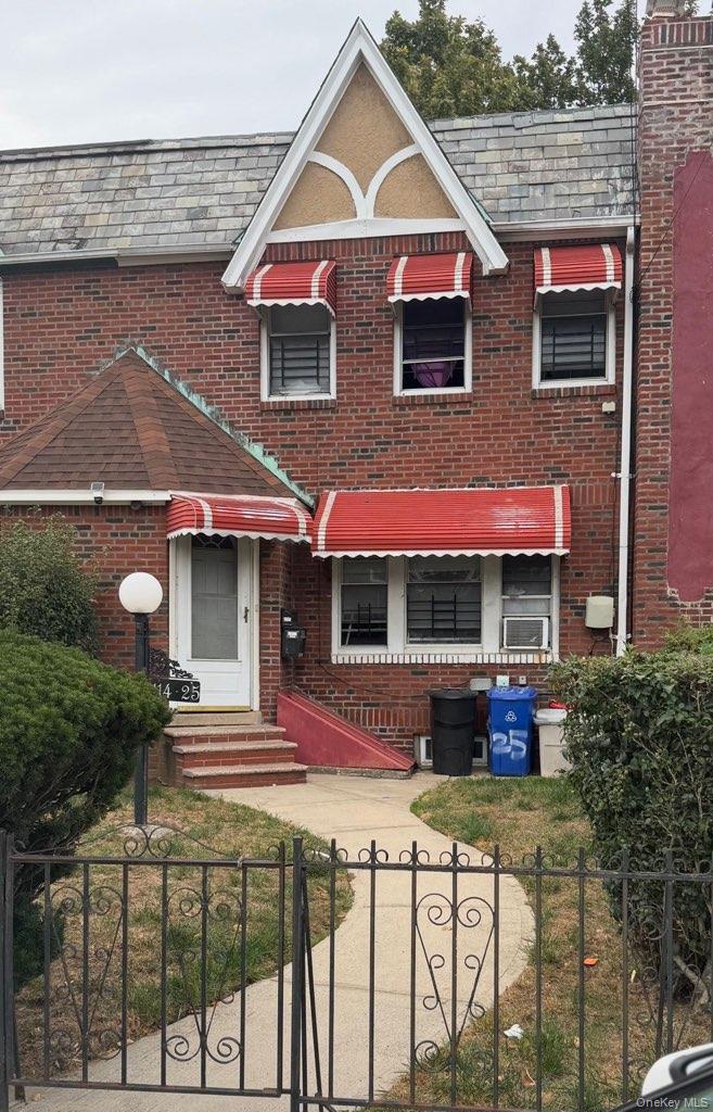 View of front facade with a high end roof, a fenced front yard, a gate, and brick siding