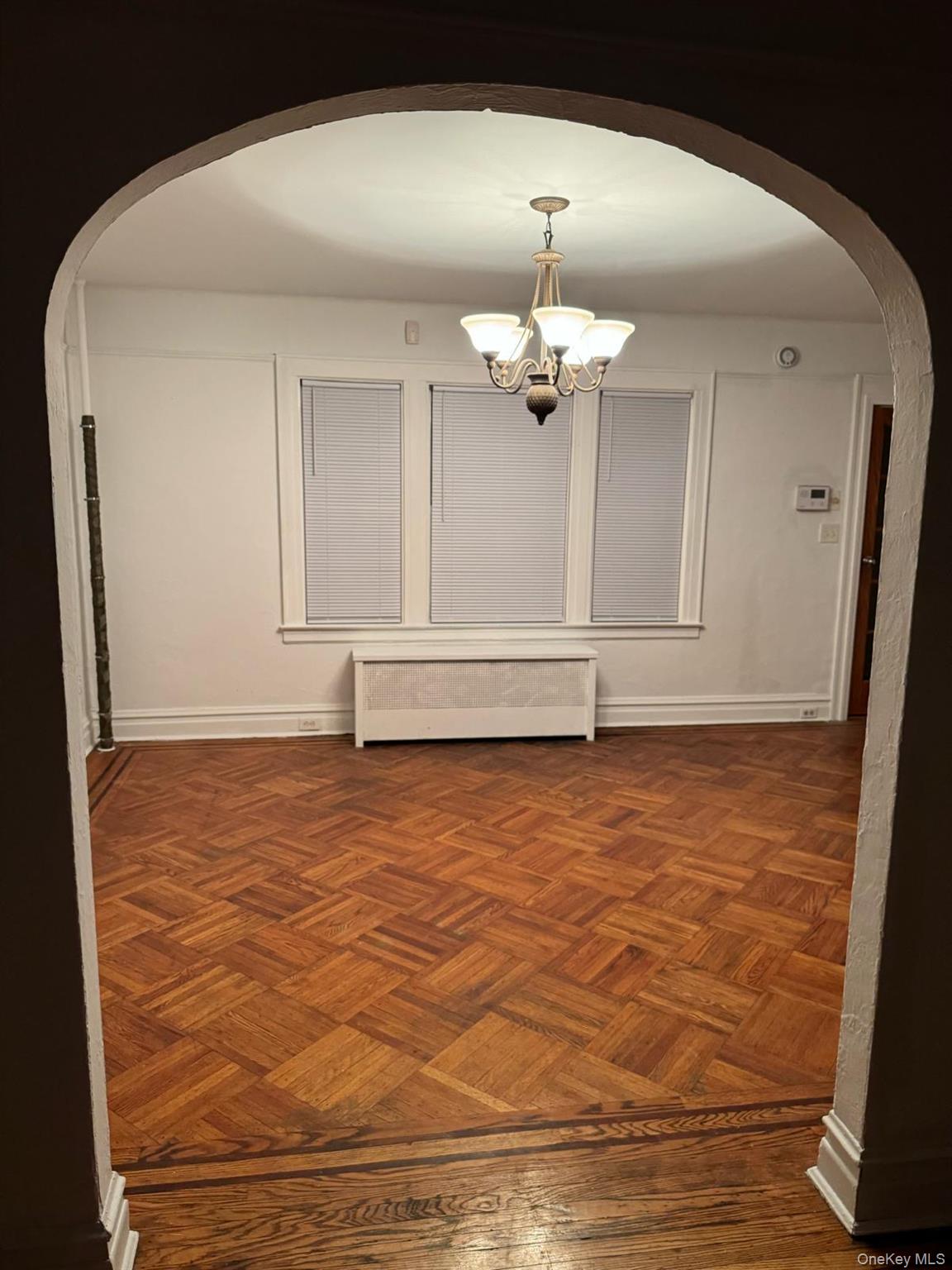114-25 201st Street Queens, NY 11412 - Photo 5 of 18 Hall featuring arched walkways, radiator heating unit, and a chandelier