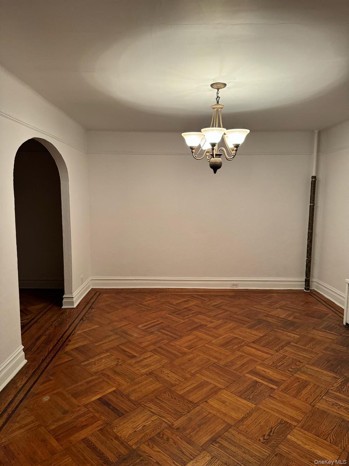 114-25 201st Street Queens, NY 11412 - Photo 6 of 18 Spare room featuring arched walkways and a chandelier