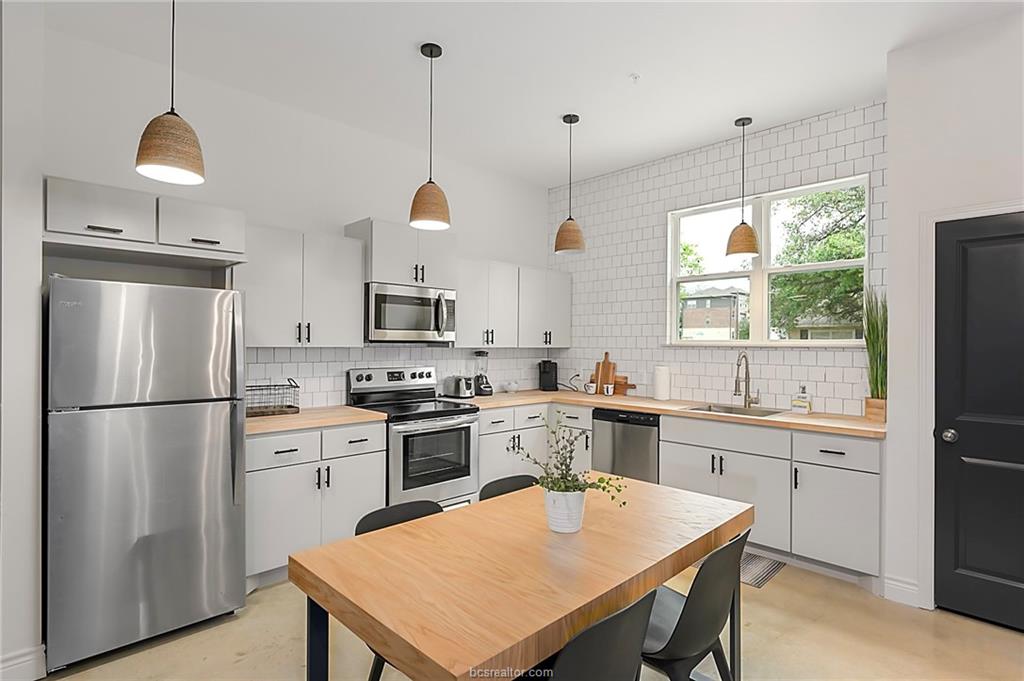 603 South Sims Avenue, Unit 113 Bryan, TX 77803 - Photo 5 of 10 a kitchen with stainless steel appliances granite countertop a stove a sink a refrigerator a kitchen island a sink a refrigerator and white cabinets
