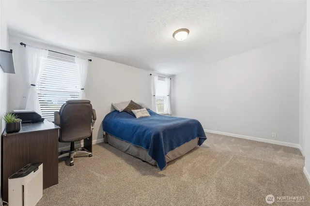 a spacious bedroom with a bed and chair