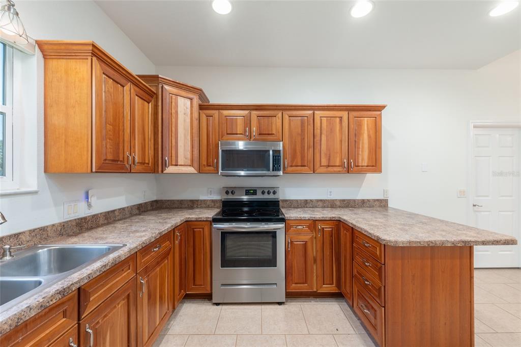 4735 Southeast 112th Street Road Belleview, FL 34420 - Photo 27 of 73 a kitchen with granite countertop a sink stove and cabinets