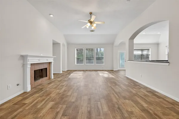 a view of an empty room with wooden floor fireplace and a window