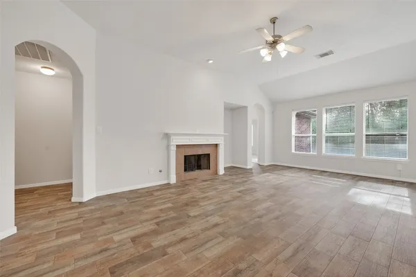 a view of an empty room with window and wooden floor