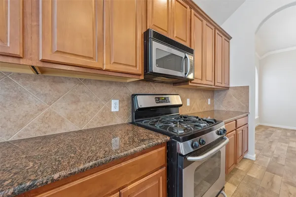a kitchen with stainless steel appliances granite countertop white cabinets and a stove top oven