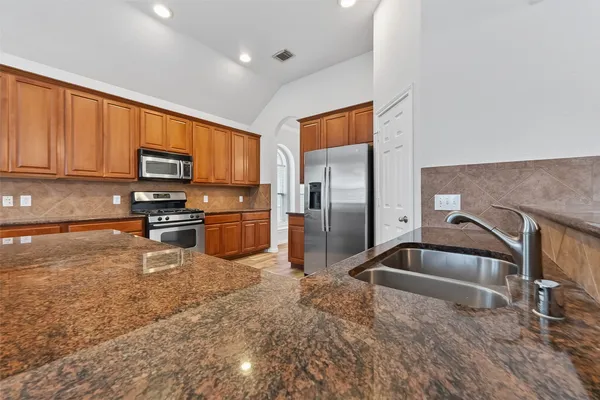 a kitchen with stainless steel appliances granite countertop a sink and a stove top oven