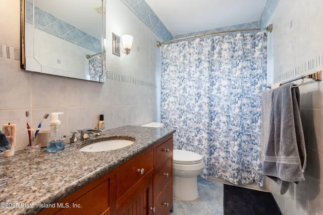 a bathroom with a granite countertop sink and a toilet
