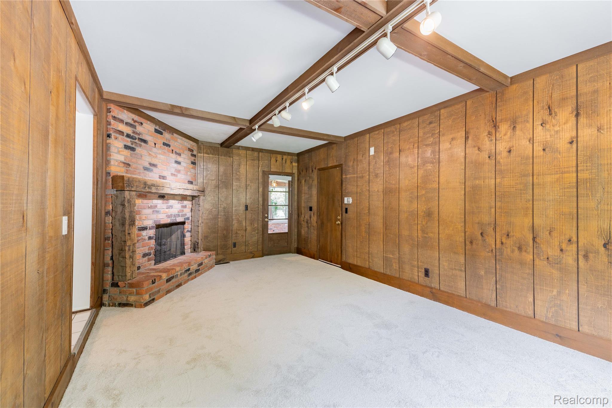 7611 Ferry Road Grosse Ile, MI 48138 - Photo 27 of 51 Spacious room featuring wood-paneled walls, exposed wood beams, and a brick fireplace with a wood mantle