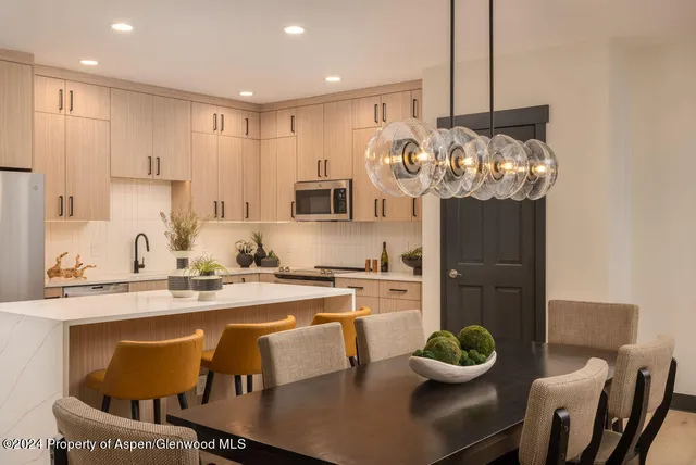 a kitchen with stainless steel appliances granite countertop a sink a stove and a dining table with wooden floor