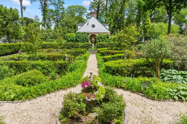 a view of a white house with a large space and a road