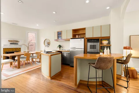 a living room with furniture a dining table and kitchen view with wooden floor