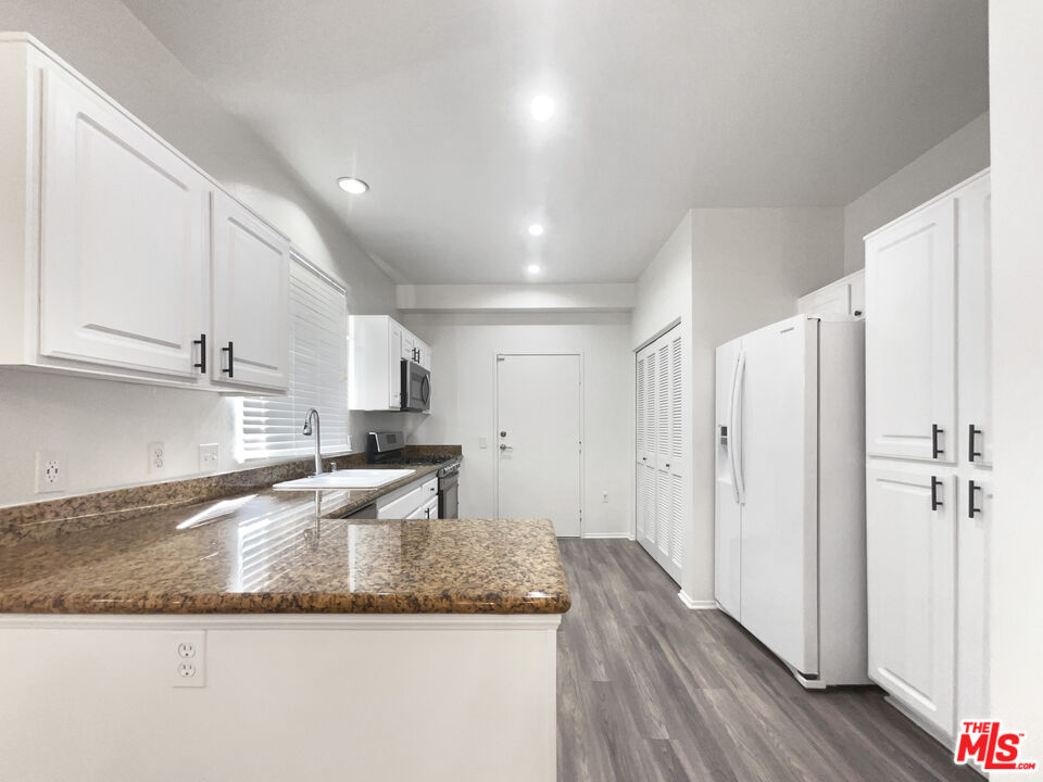 20000 Plum Canyon Road, Unit 1815 Santa Clarita, CA 91350 - Photo 13 of 21 a large kitchen with granite countertop a sink a stove and refrigerator