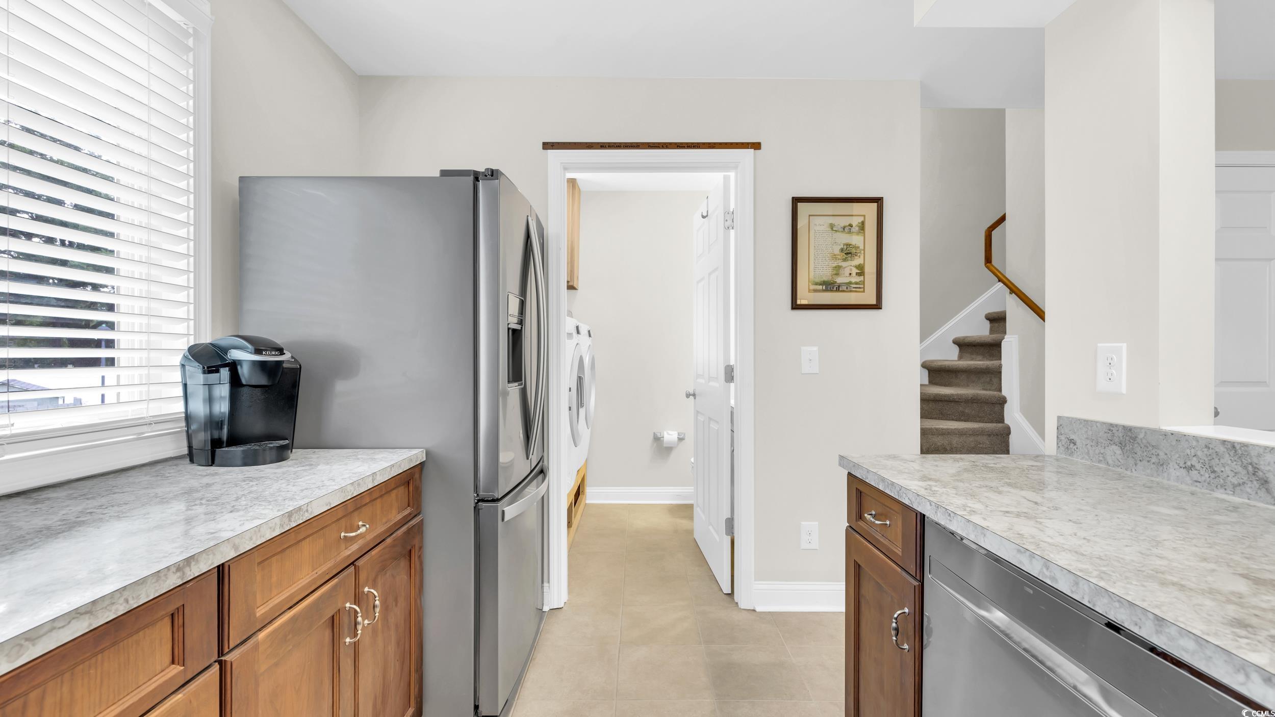 5137 Highway 17 Business, Unit 2B Murrells Inlet, SC 29576 - Photo 16 of 32 Kitchen with appliances with stainless steel finishes, light countertops, brown cabinets, light tile patterned floors, and washer and dryer