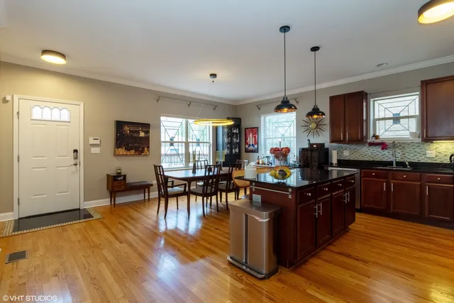 a kitchen with granite countertop a stove top oven a dining table and chairs with wooden floor